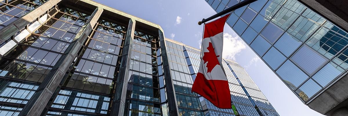 Tall buildings with a canada flag waving in the wind
